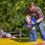 Father helping a child enjoy the jumping pillow at Woodchip Campground in Michigan