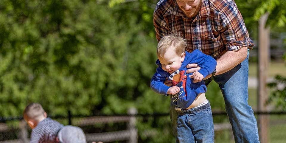 Father helping a child enjoy the jumping pillow at Woodchip Campground in Michigan