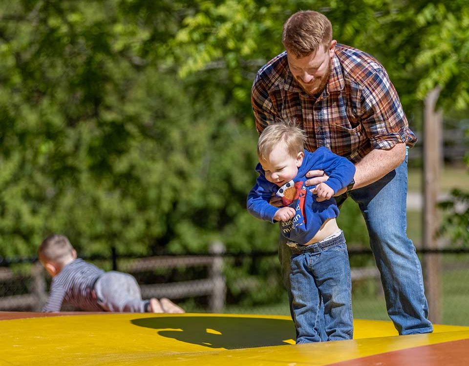 Father helping a child enjoy the jumping pillow at Woodchip Campground in Michigan